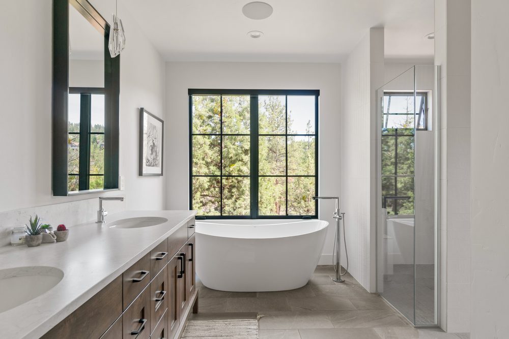 Primary bath with freestanding tub, double vanity, and picture window