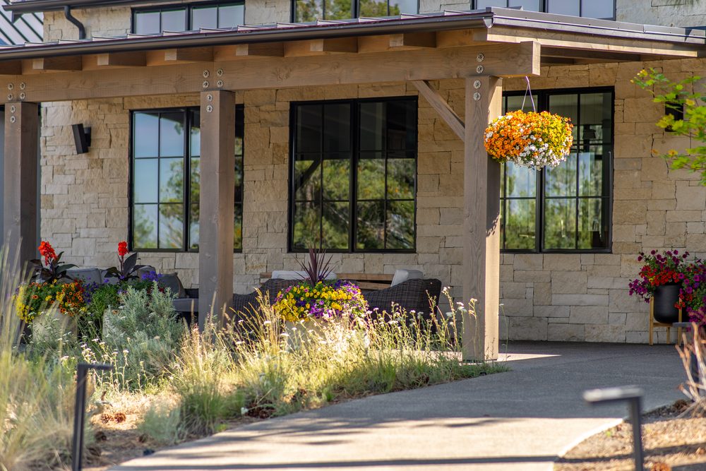 Stone-clad front porch with hanging flower baskets and landscaped entry